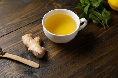 Cup of ginger tea with mint on wooden background