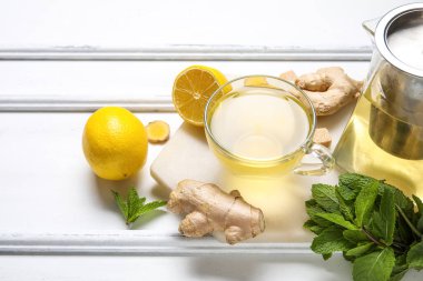 Beyaz arka planda limon ve nane aromalı bir bardak zencefil çayı.