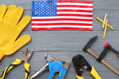 Composition with different tools, gloves and USA flag on grey wooden background. Labor Day celebration