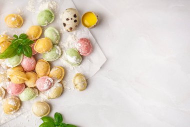 Renkli çiğ hamur köfteleri ve beyaz arka planda fesleğenli fırın kağıdı.