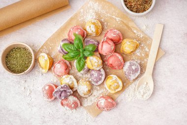 Renkli çiğ hamur köfteleri ve beyaz arka planda fesleğenli fırın kağıdı.