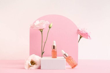Gerekli yağ şişeleri, sıva podyumu ve pembe arka planda güzel Eustoma çiçekleri olan kompozisyon