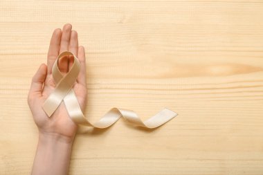 Açık tahta arka planda bej kurdeleli bir kadın. Rahim kanseri farkındalığı