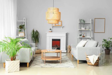 Şömineli ve gri koltuklu aydınlık oturma odasının içi.