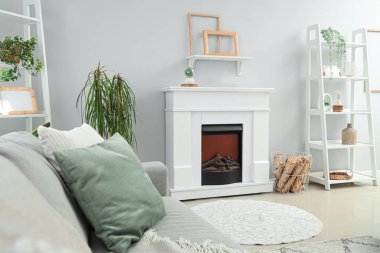 Şömineli ve gri kanepeli, aydınlık oturma odasının içi.