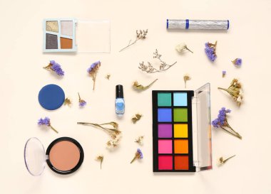 Farklı makyaj ürünleri ve açık arkaplanda güzel çiçekler olan kompozisyon