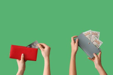 Female hands with credit cards, wallets and money on green background