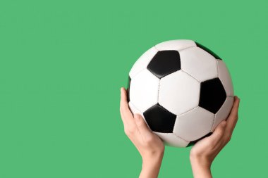 Female hands with soccer ball on green background