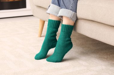 Evde örülmüş yeşil çoraplı bir kadın var.