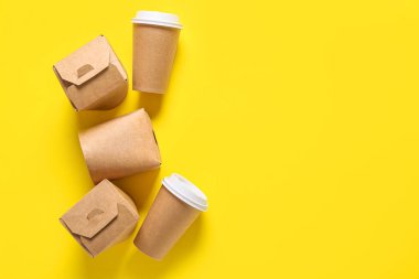 Sarı arka planda paket kâğıt bardak ve kutular