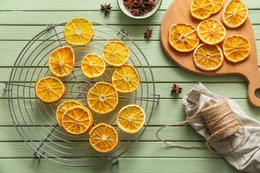 Board and stand with dried orange slices on green wooden background