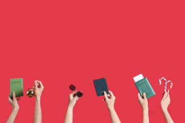 Female hands holding passports, sunglasses and candy canes on red background. New year vacation concept