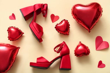 Composition with stylish female shoes, heart-shaped balloons and paper decor on color background. Valentine's Day celebration