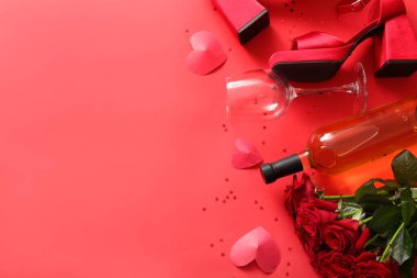 Composition with female shoes, bottle of wine and rose flowers for Valentine's Day celebration on red background