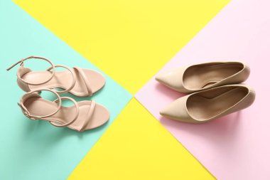 Stylish high-heeled shoes on color background