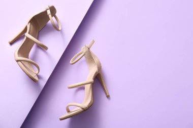 Pair of stylish high-heeled shoes on lilac background