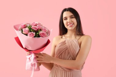 Beautiful young woman with bouquet of roses for Valentine's day on pink background