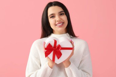 Beautiful young woman with gift for Valentine's day on pink background