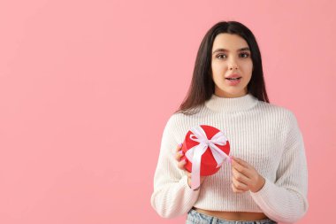 Beautiful young woman with gift for Valentine's day on pink background