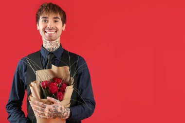 Handsome young man with bouquet of roses for Valentine's day on red background