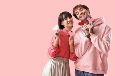 Young couple with paper hearts on pink background. Valentine's day celebration
