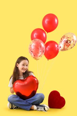 Cute little girl with heart-shaped air balloon and gift for Valentine's day on yellow background