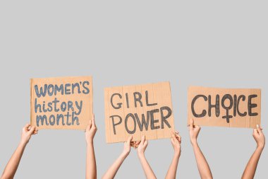 Female hands holding cardboard pieces with text CHOICE, GIRL POWER and WOMEN'S HISTORY MONTH on grey background