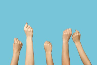 Female hands with clenched fists on blue background. Women history month