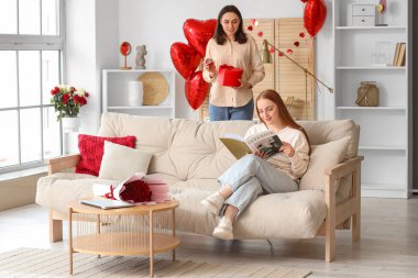 Young lesbian woman proposing to her beloved at home on Valentine's Day
