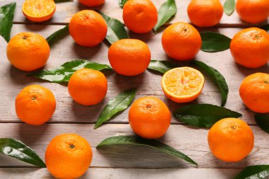 Sweet mandarins and leaves on grey wooden background