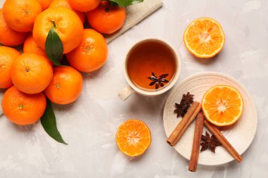 Sweet mandarins, star anise, cinnamon and cup of tea on grey background
