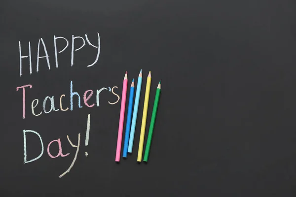 Colorful pencils and text HAPPY TEACHER\'S DAY on black chalkboard