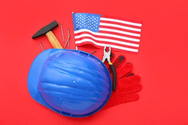 Hardhat with different tools and USA flag on red background. Labor Day celebration