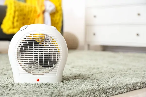 Electric fan heater on soft carpet in living room, closeup