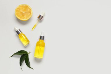 Hafif arka planda bitkiler bulunan limon yağı şişeleri.