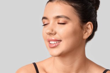 Açık arkaplanda güzel dudakları olan genç bir kadın, yakın plan.