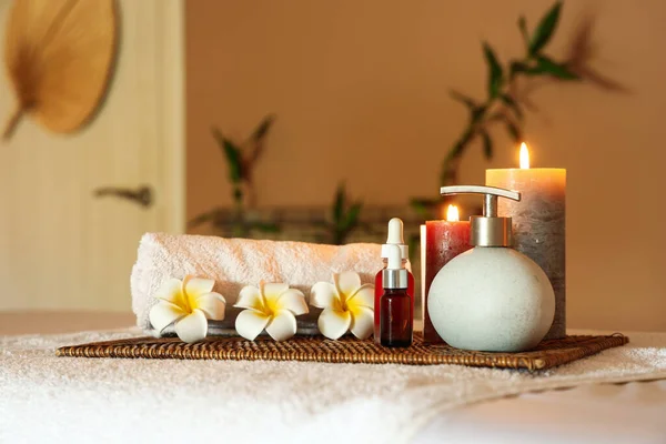Spa composition with burning candles and flowers on couch in salon, closeup