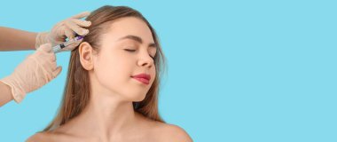 Genç bir kadın mavi arkaplana karşı metin için boşluk ile doldurma enjeksiyonu alıyor