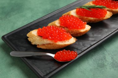 Yeşil arka planda kırmızı havyarlı lezzetli bruschettalar.