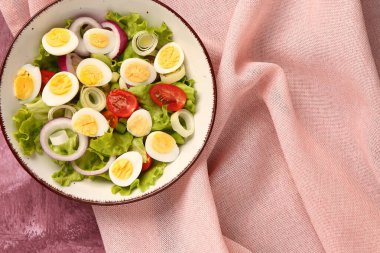 Bıldırcın yumurtalı, domatesli, soğanlı ve pembe arkaplanlı lezzetli salata.