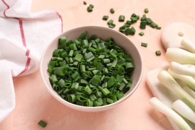 Pembe arka planda taze yeşil soğanlı bir kase dilimler ve yiyecek.