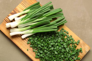 Kahverengi zemin üzerinde taze soğan dilimleri olan tahta.