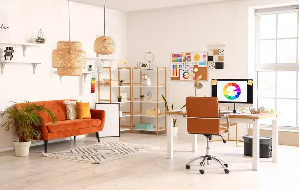 Interior of office with graphic designer\'s workplace, shelves and sofa