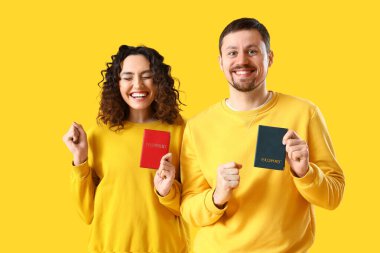 Sarı arka planda pasaportları olan mutlu genç bir çift.