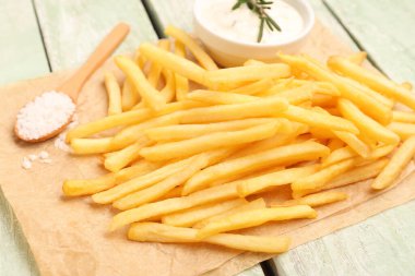 Lezzetli patates kızartması, mayonez ve yeşil ahşap arka planda tuz.