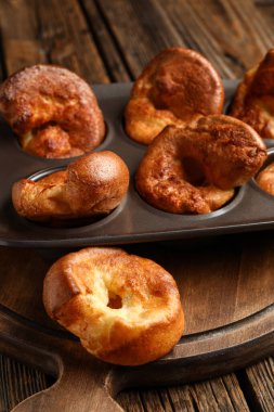 Ahşap arka planda lezzetli Yorkshire pudingi olan teneke fırın.
