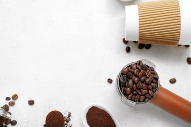 Hafif arkaplanda kahve çekirdekleri olan bardak ve portafilter.