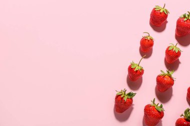 Pembe arka planda bir sürü taze çilek