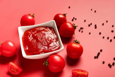 Kırmızı arka planda domates ezmesi ve taze sebzeli kase.