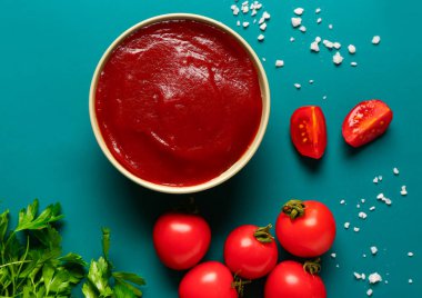 Mavi arka planda domates ezmeli ve taze sebzeli kase.